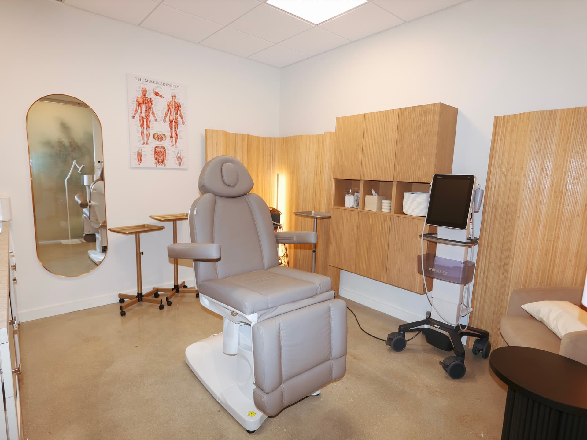 A treatment room at Evolve Longevity with a powered procedure chair and a rolling device cart.