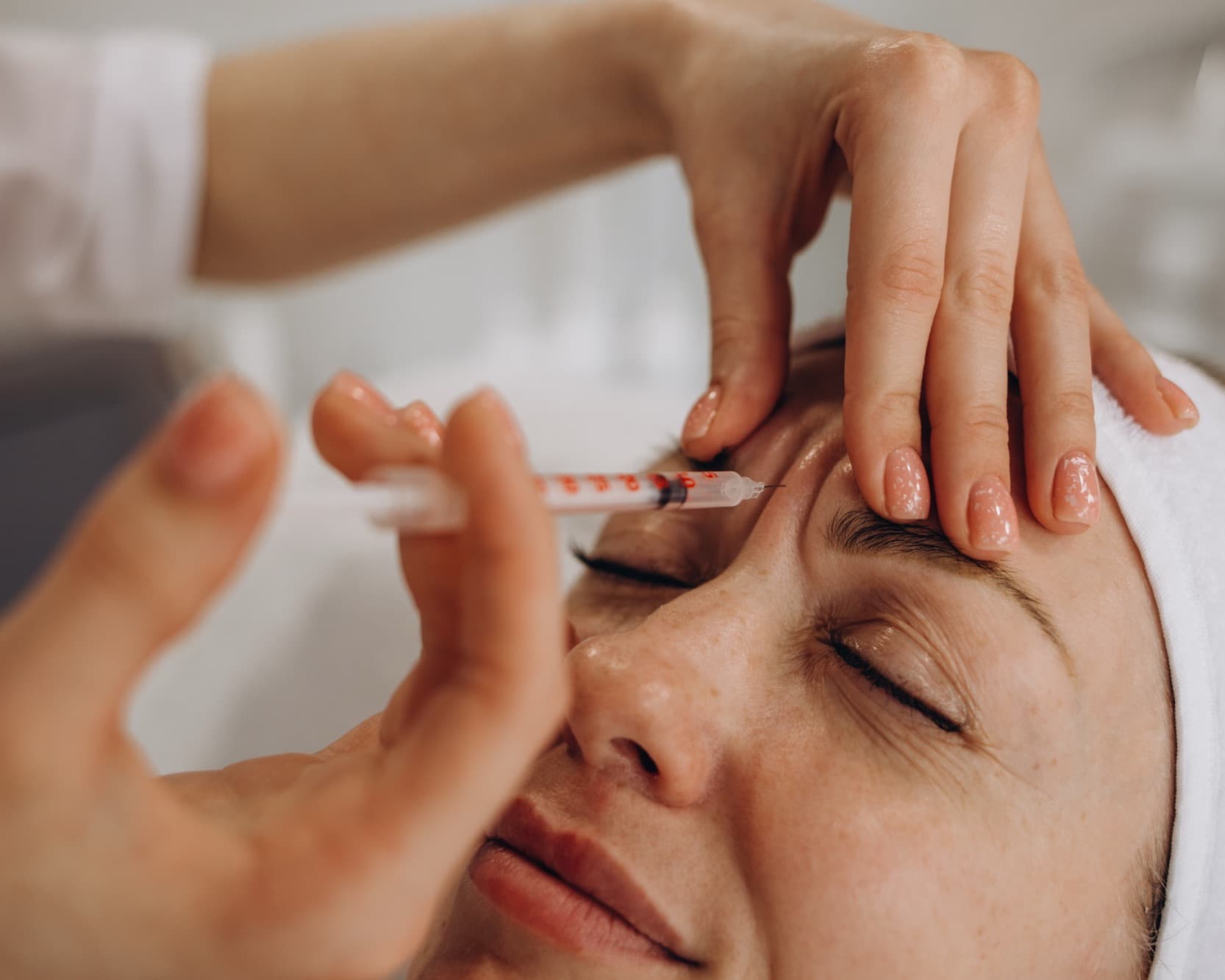 Close-up of a clinician injecting Botox near a patient brow
