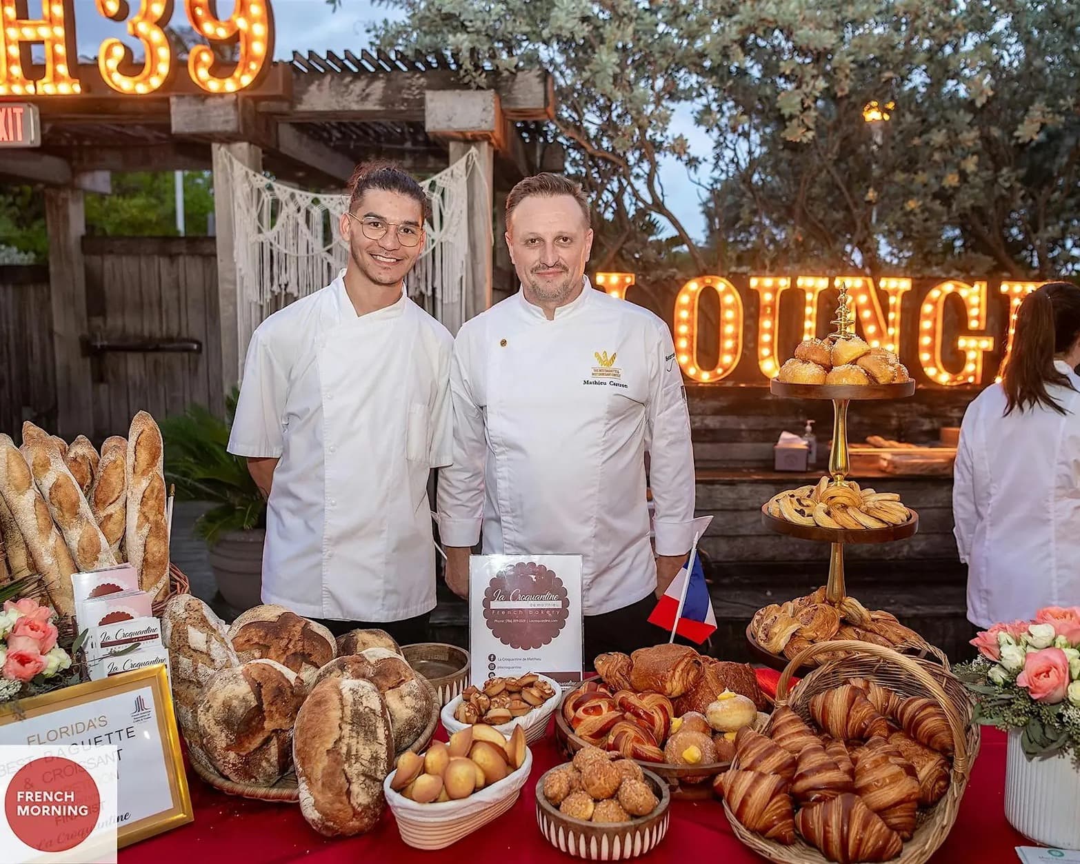 Two bakers behind a display of baguettes, croissants, and pastries at Florida’s Best Baguette and Croissant competition
