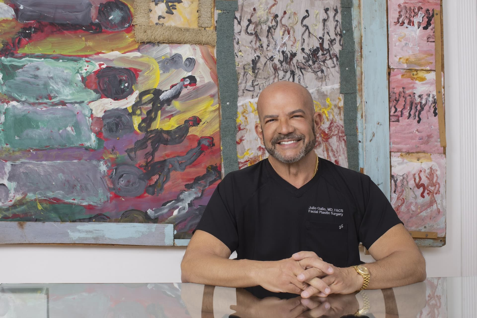 Dr. Julio Gallo seated in front of a colorful painting