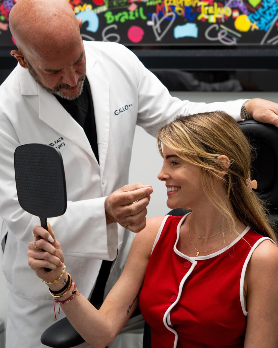 Dr. Julio Gallo assesses a patient holding a hand mirror