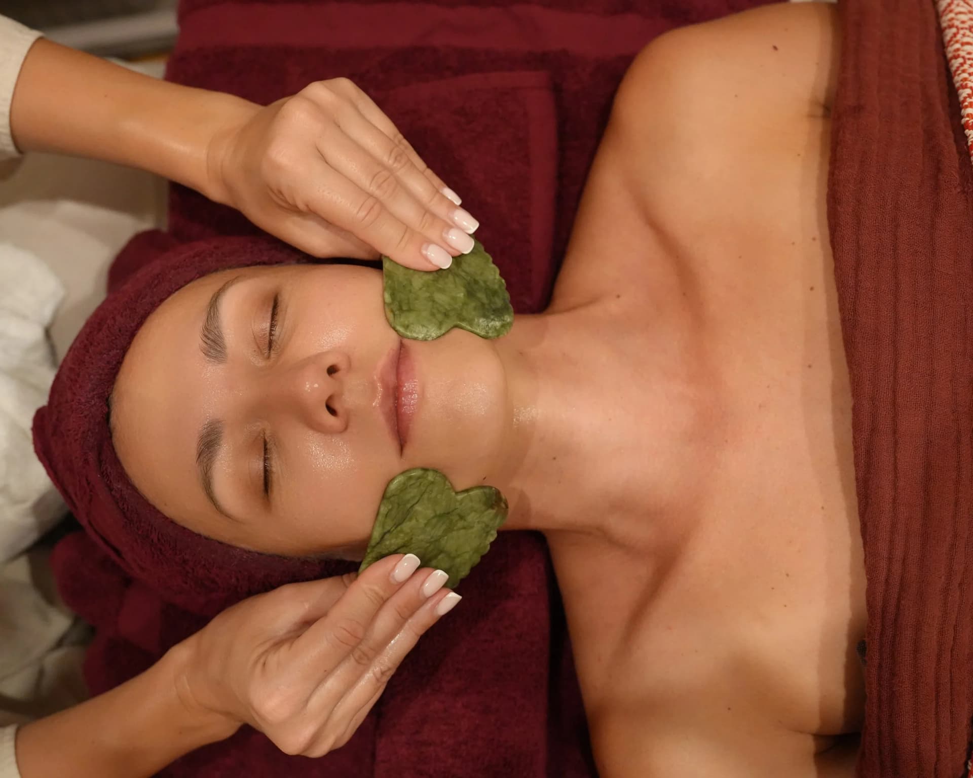 A gua sha facial treatment underway at Da Beauty Bar, with jade tools worked along the client's cheek